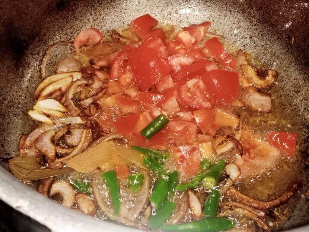 Adding tomatoes and green chilies